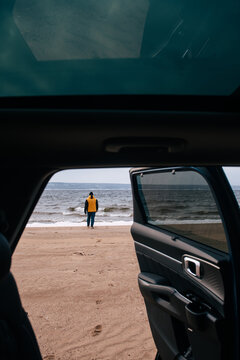 man in a yellow jacket watching at the cold sea