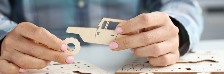 Female hands assemble wooden toy car from different parts