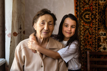 Little baby girl and very old woman. Little child hugging grandmother. Granddaughter