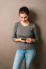 Trendy casual young woman standing watching media on her phone