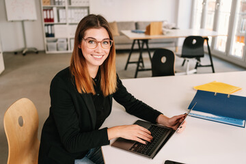 Smiling friendly young woman working in an office