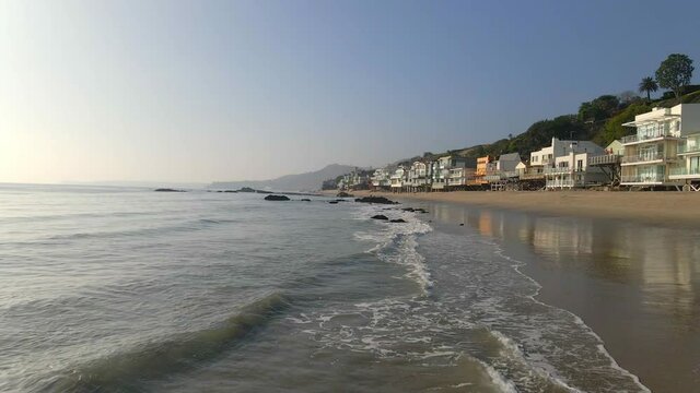 Waves rolling at Malibu beach residential homes facing the ocean