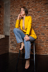   25 - year - old girl poses in   fashionable yellow jacket and jeans .