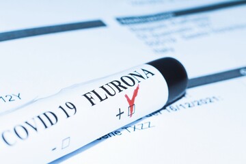 Obraz premium Blood test tube laying on a medical paper certificating positivity to Flurona variant