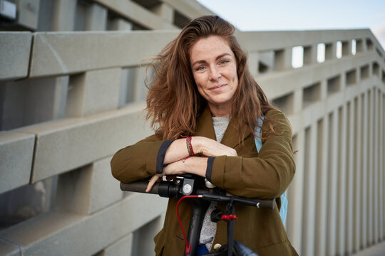 Positive woman leaning on e scooter