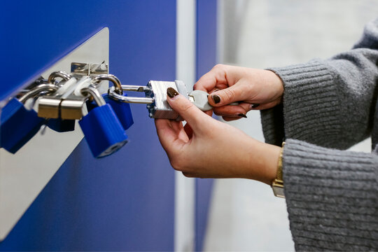 Anonymous woman opening padlocks on a blue door of a storage roo