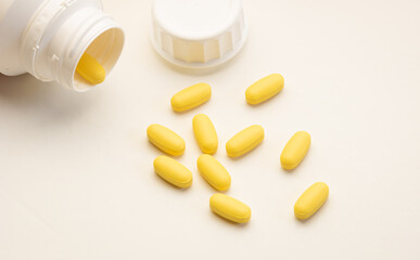 Open pot of yellow pills spread on the surface