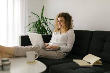 Smiling woman studying online from home using laptop
