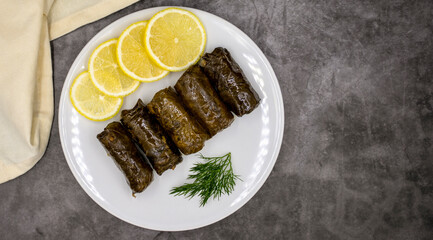 Stuffed grape leaves with olive oil on a dark background. Traditional Turkish cuisine delicacies. Delicious dolma (yaprak sarma). Top view. Copy space. Empty space for text
