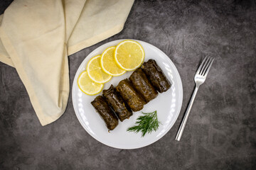 Stuffed grape leaves with olive oil on a dark background. Traditional Turkish cuisine delicacies. Delicious dolma (yaprak sarma). Top view. Close up