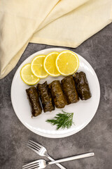 Stuffed grape leaves with olive oil on a dark background. Traditional Turkish cuisine delicacies. Delicious dolma (yaprak sarma). Top view. Close up