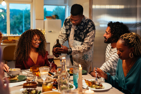 Black man pouring wine for friends