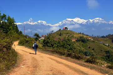 A pedestrian was walking towards his destination. Enchanting mountains with enchanting spirits, Annapurna and fish tail with a temple. The photo was taken in Salme hill of Syangja district.