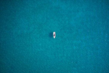 White boat with people aerial view. People in a boat at anchor top view. White big boat on turquoise water aerial view.