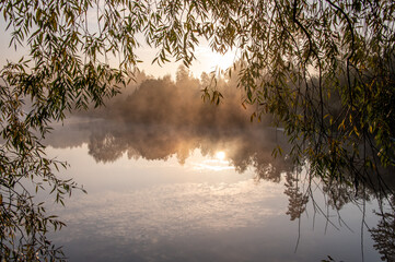 Beautiful landscape of the mirror on the lake during sunrise framed with tree. Light fog over the water. Specular reflection in the water in autumn. Concepts: nature, landscape, scenery