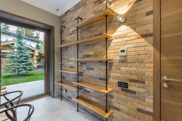 The original design of the room with a panoramic window and shelves on the brick wall.