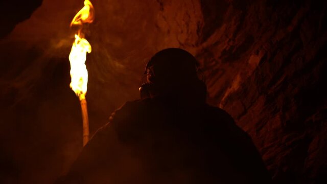 Man being trapped in a dark cave at night with a burning flickering torch