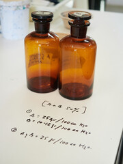 antique chemistry amber flasks on white table with handwritten chemical formulas