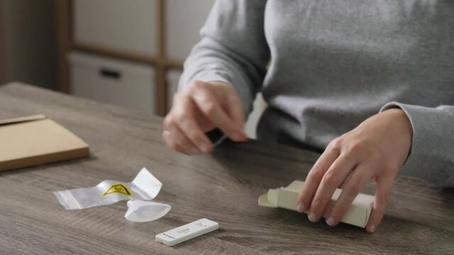 medicine, quarantine and pandemic concept - hands of woman unpacking coronavirus saliva test kit at home