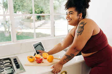 Fitness woman with digital tablet and fruits in kitchen