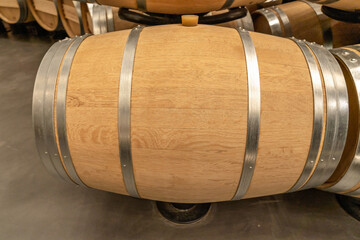Yellow oak barrel with stainless steel rings at a winery for making wine. Side view. Advertising space, copy space
