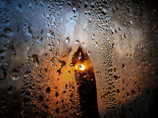 Okno w kroplach deszczy ze słońcem na pierwszym planie 