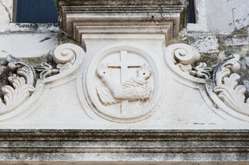 Religious symbol, Franciscan coat of arms, cross with two arms with two arms crossing each other, carved in white stone, in Zadar, Croatia - obrazy, fototapety, plakaty
