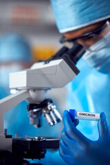 Close Up Of Female Lab Worker Wearing PPE Researching Omicron Variant Of Covid-19 With Microscope