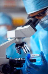 Close Up Of Female Lab Worker Wearing PPE Researching Covid-19 With Microscope