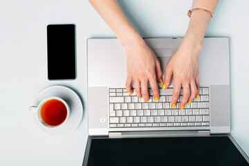 Fototapeta na wymiar A woman prints on a laptop at her desk top view