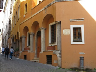 Fototapeta na wymiar Rome Street View with Historic Orange House Facade with Ancient Columns, Italy