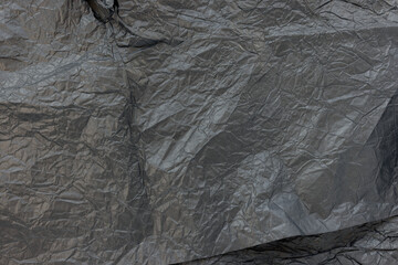 Crumpled black kraft paper for gift wrapping or packaging. Close up, texture background, pollution and recycling concept