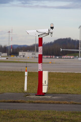 Fototapeta na wymiar Visibility measuring on red and white striped pole at runway at Zürich Airport on a cloudy winter day. Photo taken January 2nd, 2022, Zurich, Switzerland.
