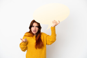 Young redhead woman isolated on white background holding an empty speech bubble with surprised expression