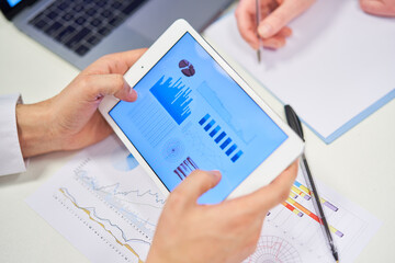 Hands hold tablet computer with graphs and charts