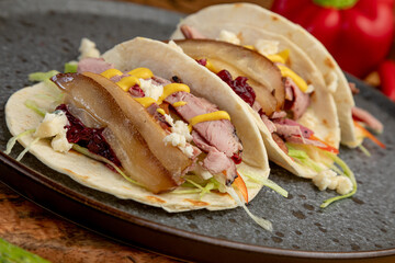 smoked meat tacos served on a black plate.