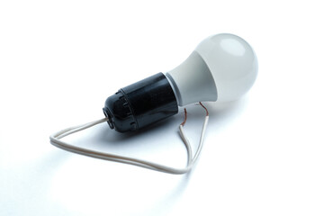Obraz premium Frosted light bulb in a black socket with wires on a light background. Close-up. Selective focus