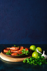 Grilled cooked argentine prawns, shrimps langoustines with herbs, garlic and lemon on a dark background with copy space