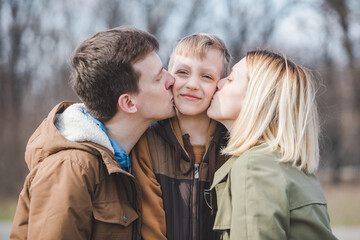 Obraz premium little boy son in the middle parent kissing in both cheeks