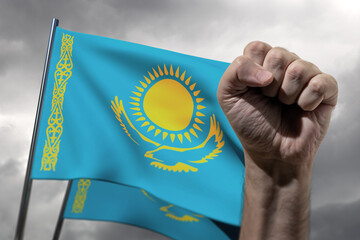 Political protests in Kazakhstan. A raised fist of a protester against the background of the national flag of Kazakhstan and a dark cloudy sky. The fight for human rights in Kazakhstan