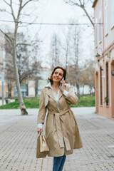 An adult woman walking through the city while talking on her mobile phone.