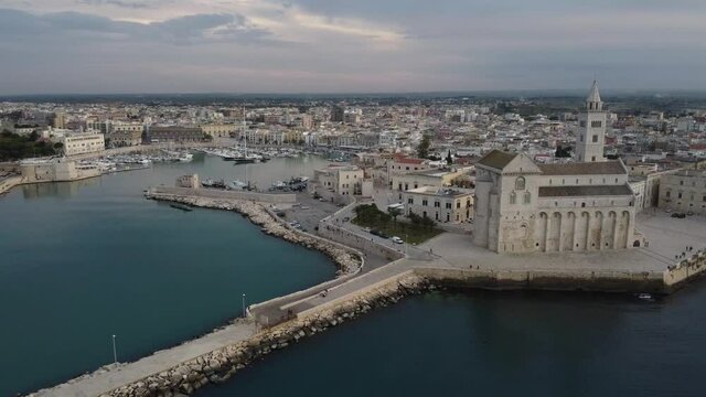 Circle e zoom out con drone sulla citt&agrave; Trani andando all'indietro ruotando da sinistra verso destra aprendo l'inquadratura dalla cattedrale verso il porto e il centro storico
