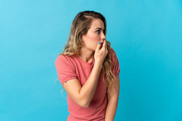 Young Brazilian woman isolated on blue background doing surprise gesture while looking to the side