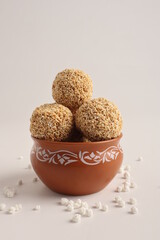 Til Gul OR Sweet Sesame seed ball or Laddu with Fikri for Indian festival Makar Sankranti over white background.
