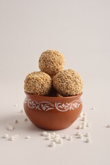 Til Gul OR Sweet Sesame seed ball or Laddu with Fikri for Indian festival Makar Sankranti over white background.