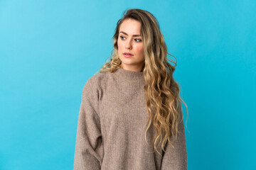 Obraz premium Young Brazilian woman isolated on blue background making doubts gesture looking side