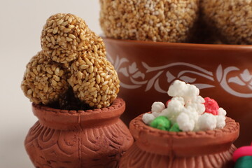 Til Gul OR Sweet Sesame seed ball or Laddu with Fikri for Indian festival Makar Sankranti over white background.