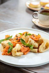 pancakes with salmon decorated with fresh herbs, served with juice. breakfast, photo of the dish in the interior