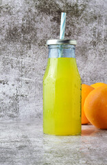 Vertical shot, glass bottle with refreshing orangeade, 
stone base in light colors and copy space.