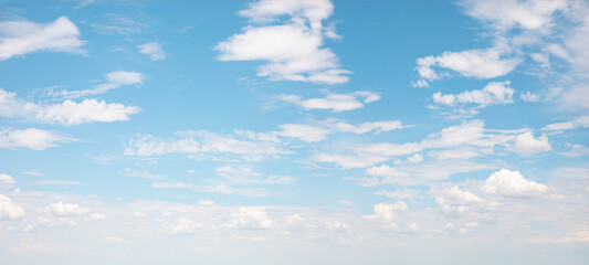 Blue sky and white clouds background - Pillowy clouds cover a blue sky in the background